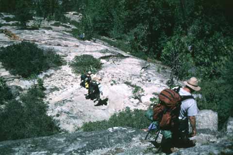 Photo, people hiking down steep rocks.