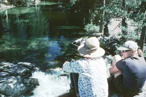 Photo, people sitting on a rock overlooking the creek.
