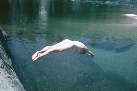 Photo, person diving off a rock into the creek.
