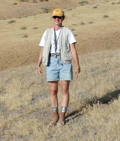 photo of geologist in field garb among grass-covered hills