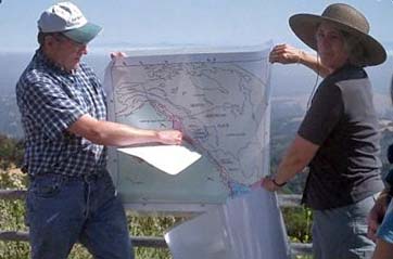 photo of two people holding a map at an overlook