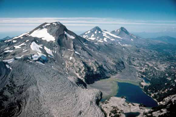 Photo of three volcanoes in a row showing a bit of snow