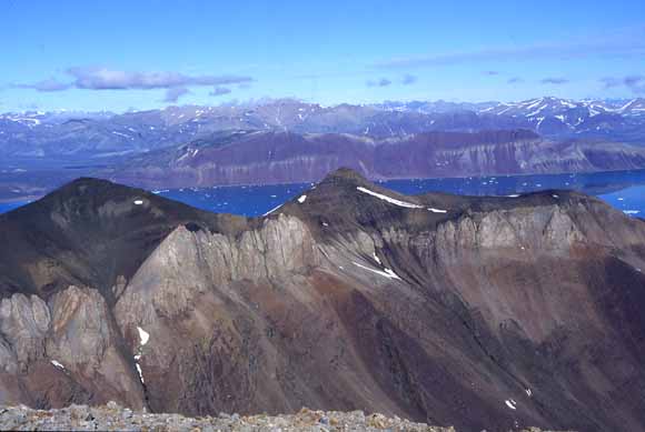 photo of rugged mountains, coastal inlet, and snow-covered peaks in the background
