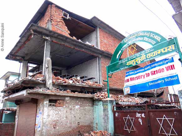 Nepali school with one of the floors visibly pancaked, other floors missing wall following April 25, 2015, earthquake