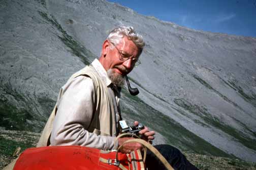 photo, Bill sitting on hillside with mountainside in background